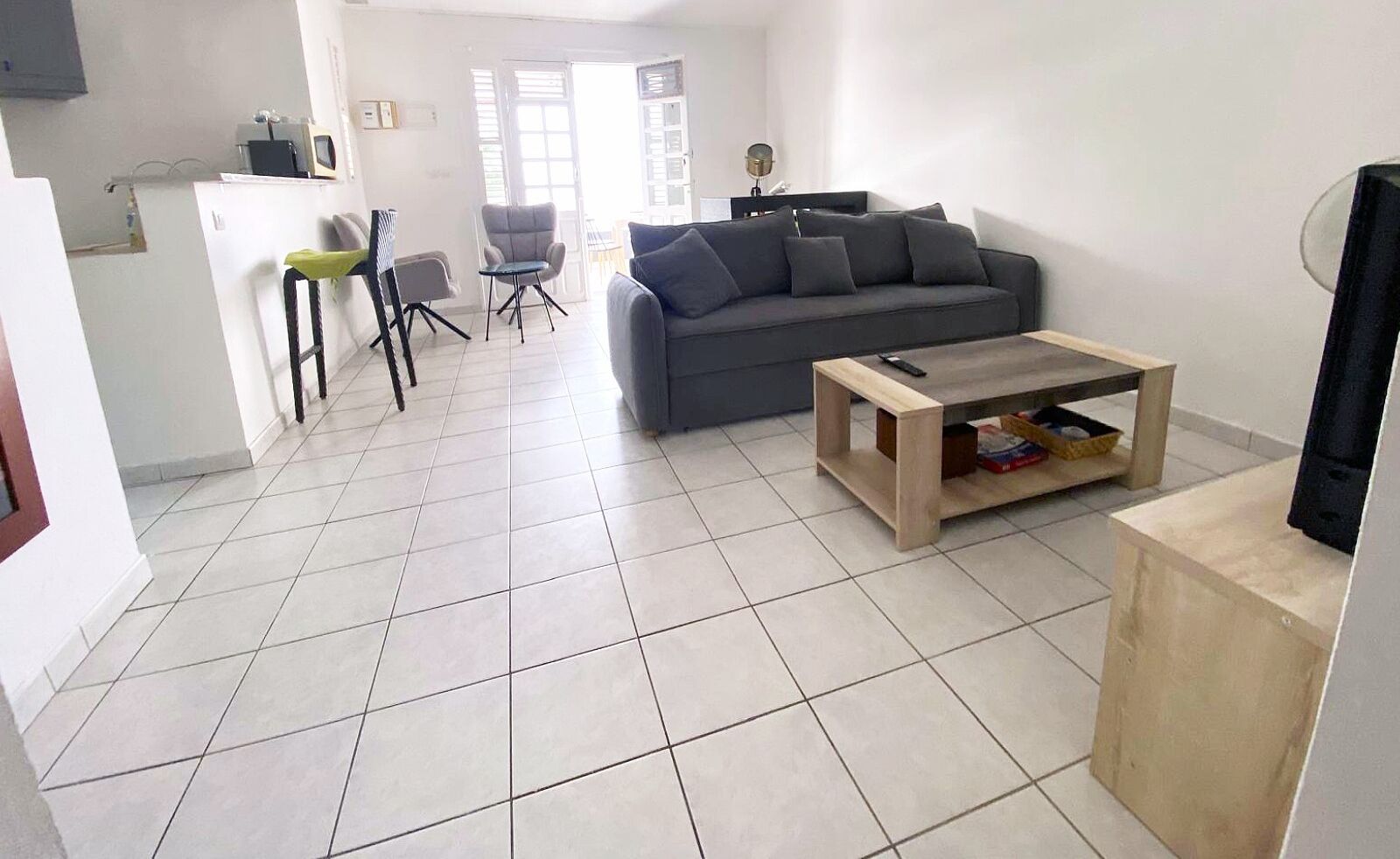 A living room with a grey sofa, a wooden coffee table, and a TV stand.