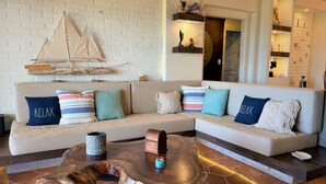Una sala de estar moderna con pared de ladrillo blanco, una mesa de centro de madera y un sofá beige con cojines coloridos.