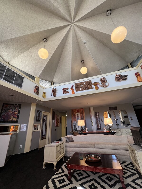 A spacious living area with a high ceiling, a central chandelier, and a sofa.