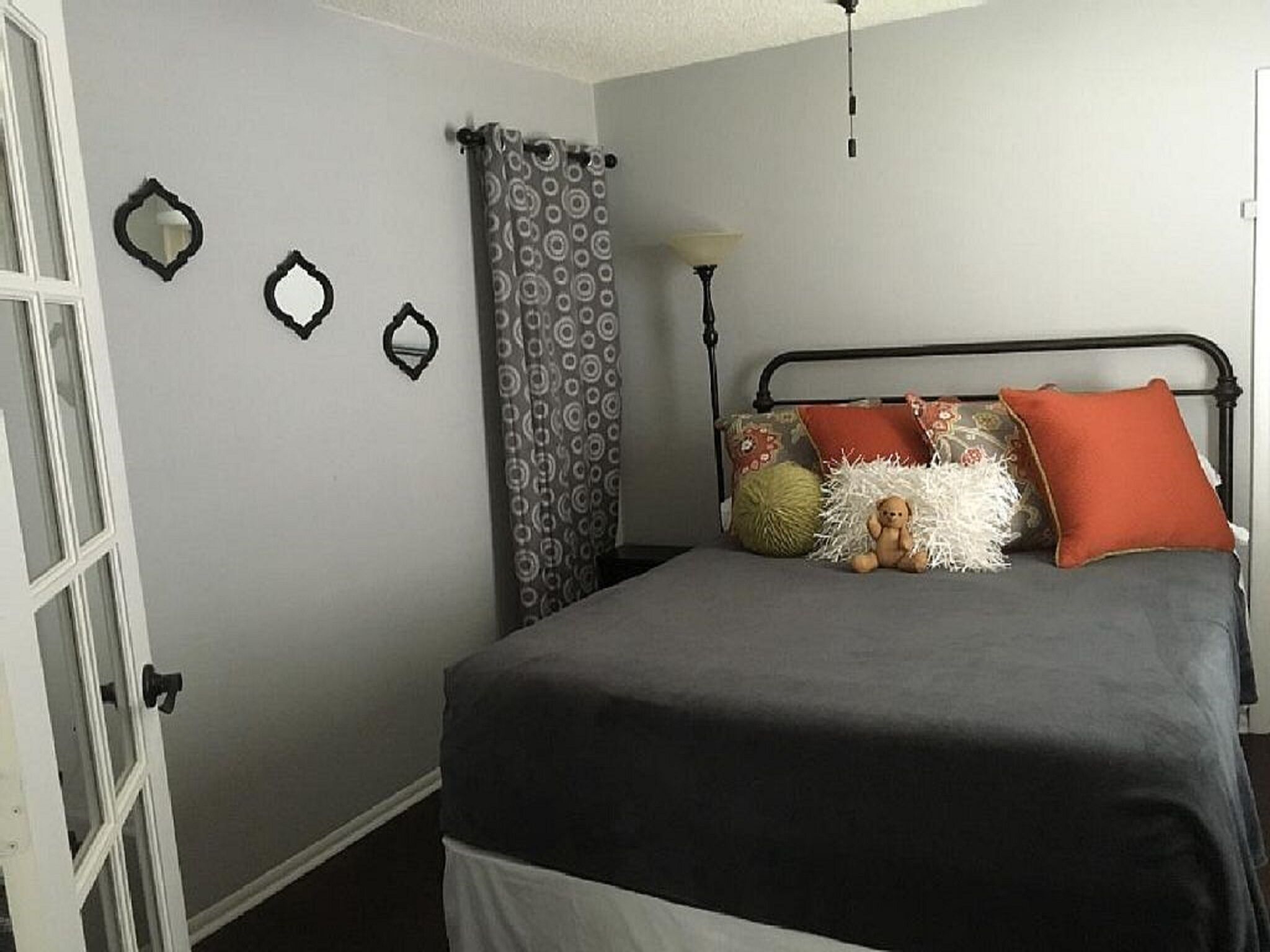 A bedroom with a bed, a lamp, and a window with curtains.