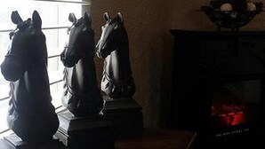 A room with three horse statues on a wooden table, a lantern on the wall, and a fireplace with a red glow. - Yellowstone Village Resort  
2 Houses  
same day bookings
Deer,Fire Pits,Swings (Cody)