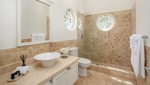 Une salle de bain avec un grand miroir, un lavabo, des toilettes et un espace douche.