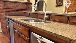 A kitchen with granite countertops, stainless steel appliances, wooden cabinets, and a brick fireplace. - Historic home in quaint town of South Pittsburg. Just off I-24. (South Pittsburg)