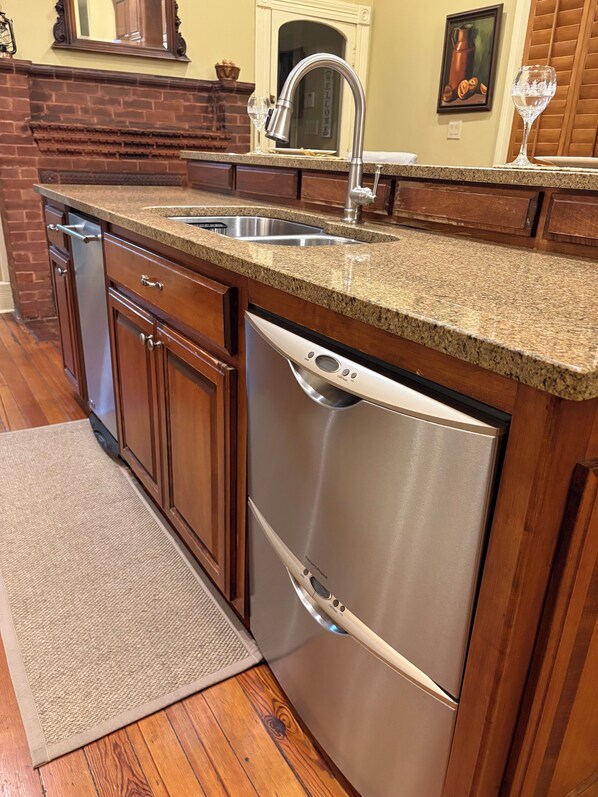 A kitchen with granite countertops, stainless steel appliances, wooden cabinets, and a brick fireplace. - Historic home in quaint town of South Pittsburg. Just off I-24. (South Pittsburg)