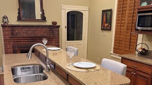 A kitchen with granite countertops, a stainless steel sink, wooden cabinets, a brick fireplace, and pendant lighting. - Historic home in quaint town of South Pittsburg. Just off I-24. (South Pittsburg)