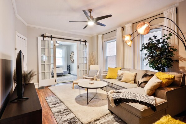 A modern living room with a sofa, coffee table, and a TV on a stand.