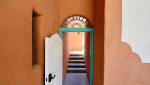 A hallway with a white door and a turquoise frame leading to a staircase. - Zona Rosa 77, Santiago (Santa Fe)