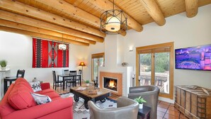 A cozy living room with a fireplace, wooden ceiling beams, a red sofa, and a television. - Zona Rosa 77, Santiago (Santa Fe)
