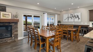 A spacious dining area with a stone fireplace, wooden dining table, and chairs. - Indoor/Outdoor Pool,Hot Tub, Firepit,Game Room, Pickleball, Pool Table,Lakeview (Branson)
