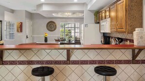 A kitchen with a wooden countertop, two bar stools, a refrigerator, and cabinets. - Legacy Walk-in - Golf Views Great Location (Branson)