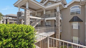 A multi-story building with a stone facade, multiple balconies, and a covered outdoor area. - Legacy Walk-in - Golf Views Great Location (Branson)