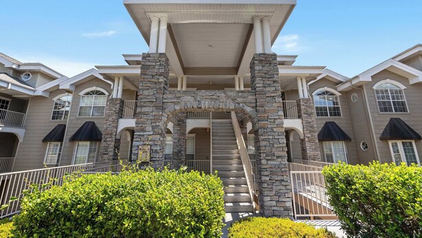 A multi-story building with a central staircase, stone pillars, and a covered entrance. - Legacy Walk-in - Golf Views Great Location (Branson)