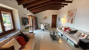 A spacious living room with a high ceiling, a sofa set, a coffee table, and a TV. - Penthouse Andrea apartment with private pool (Meina)