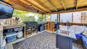 A covered outdoor kitchen area with a grill, storage containers, and a television.