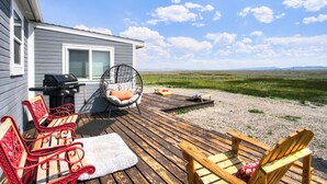 Een terras met buitenmeubilair, een barbecue en een hangstoel.