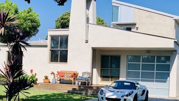 Una casa moderna con fachada blanca, ventanas grandes y un camino de entrada.