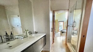 Un baño moderno con un espejo grande, un tocador espacioso y suelo de madera.