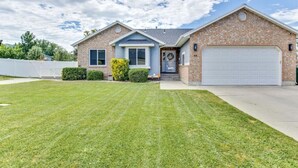 Une maison à deux étages avec une façade en briques, un garage à l’avant et une pelouse bien entretenue.