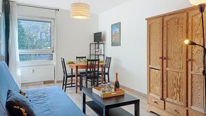 Une pièce avec un canapé bleu, une table à manger avec des chaises, un meuble en bois et un téléviseur posé sur un meuble.