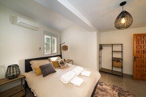 Een slaapkamer met een bed, nachtkastjes, een hanglamp, een raam en een kledingkast.