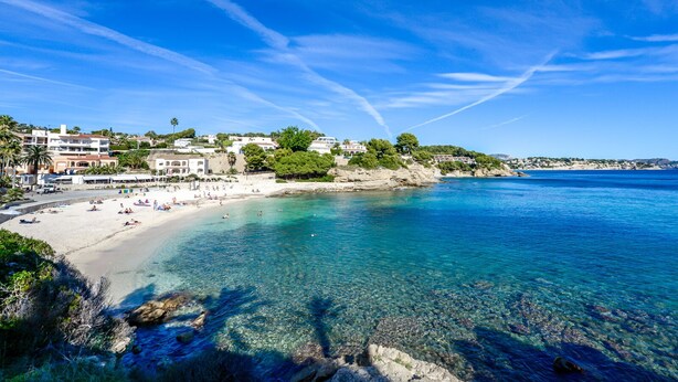 Uma cidade costeira com mar azul-turquesa, praia de areia e edifícios ao longo da costa.
