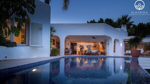 Eine moderne Villa mit Schwimmbad, Sitzbereich im Freien und einer überdachten Terrasse.