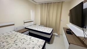 A hotel room with a bed, a TV, and a desk with a remote control. - POUSADA BRILHO DO MAR (Maraú)
