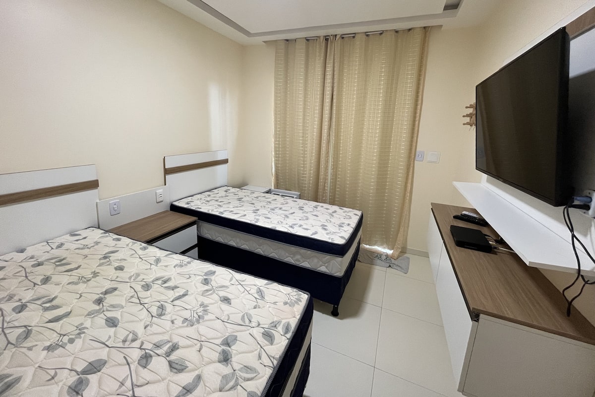 Una habitación de hotel con una cama, un televisor y un escritorio con un control remoto.