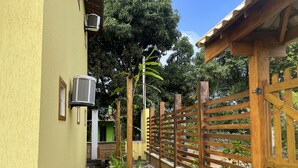 A narrow outdoor corridor with a wooden bench, a metal fence, and a gate. - POUSADA BRILHO DO MAR (Maraú)