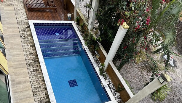 A rectangular pool with a tiled edge, surrounded by a wooden deck and a brick pathway. - POUSADA BRILHO DO MAR (Maraú)