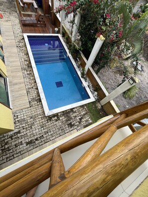 A rectangular pool with a tiled edge, surrounded by a wooden deck and a brick pathway. - POUSADA BRILHO DO MAR (Maraú)