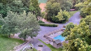 Un resort con piscina, sala de estar y vistas al bosque y lago circundantes.