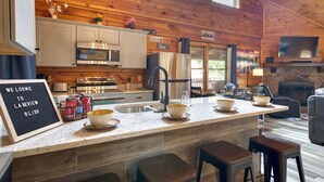 Una cocina acogedora de estilo rústico con paredes de madera, una isla grande con cuencos, y un cartel dando la bienvenida a Lakeview Bliss.