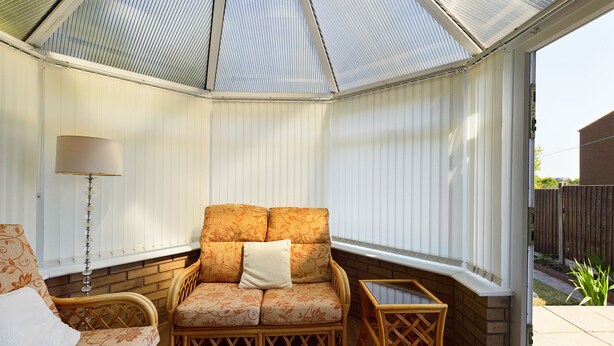 A conservatory with a cushioned bench, a small table, and a lamp. - Tranquil Telford Retreat - 3 Bedroom House (Telford)