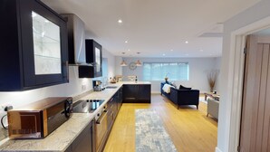 A modern kitchen with dark cabinetry, a built-in oven, and a large island with a sink.