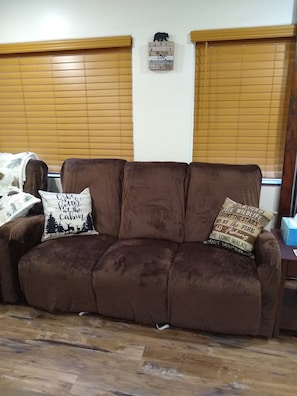 Relax in this inviting living room with a sofa, wooden headboard, and wooden floor.