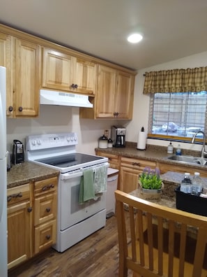 Kitchen with a window offering a view of the outside, featuring a stove, sink, and coffee maker.