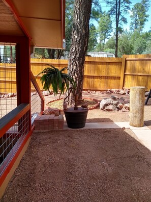 Surrounded by lush greenery, this serene outdoor space features a potted plant and a tree trunk.