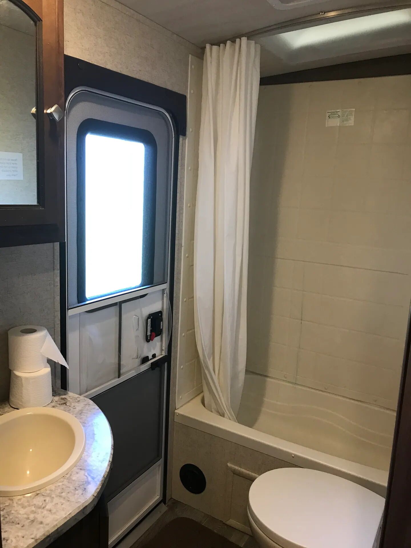 A compact bathroom with a toilet, sink, and shower.