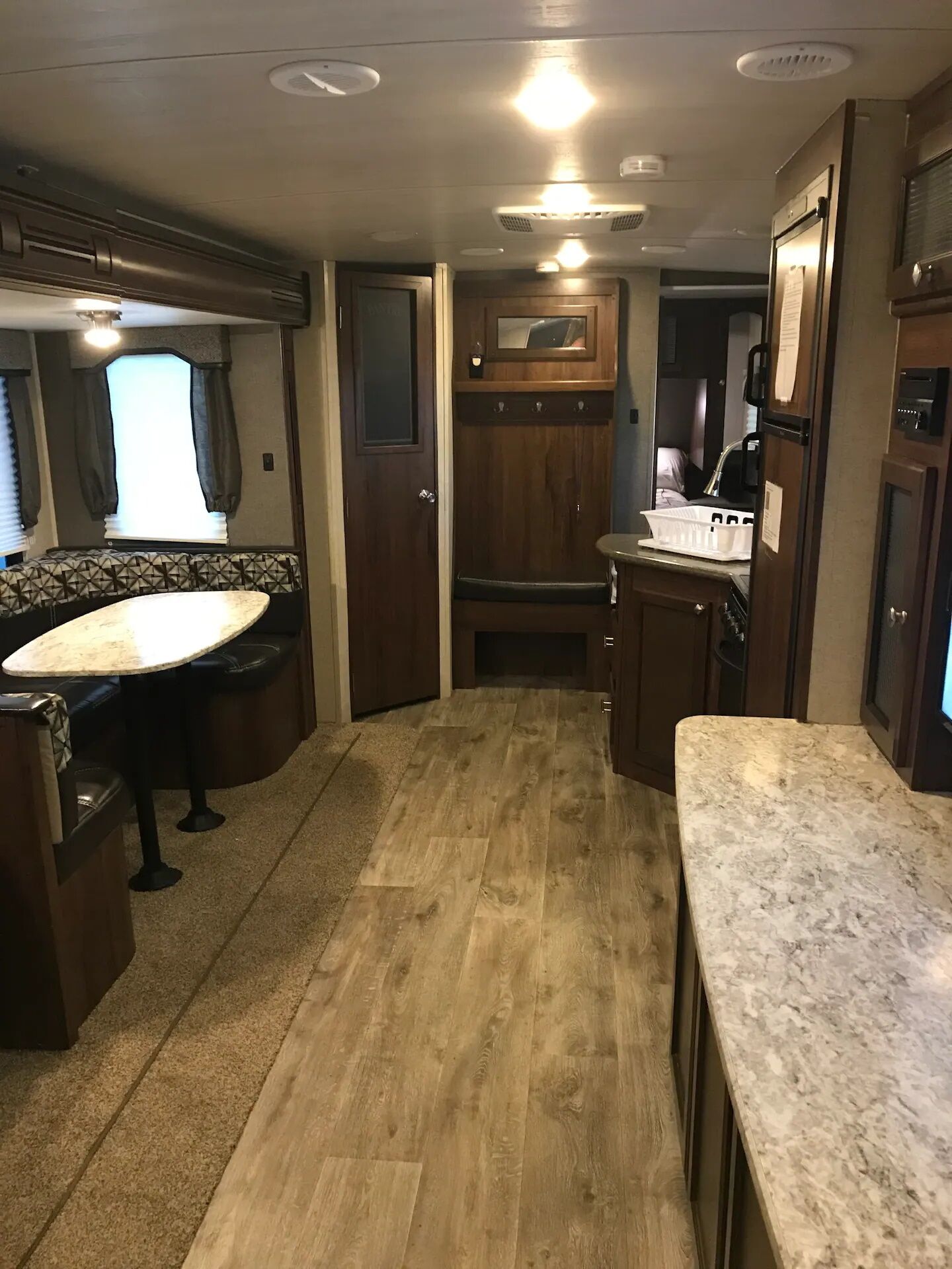 Uma cozinha compacta para motorhome, com área de refeições, armários de madeira e bancada.