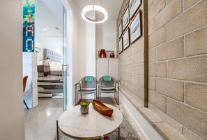A modern interior with a round table, chairs, a neon light, and a brick wall with framed pictures. - 2 Modern Units in Heart of Little Italy! (San Diego)
