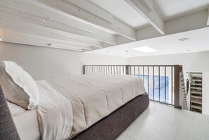 A modern bedroom with a large bed, a balcony with a railing, and a built-in closet. - 2 Modern Units in Heart of Little Italy! (San Diego)