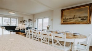 Un coin repas avec une table ronde, des chaises blanches et un tableau accroché au mur.