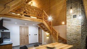 Une cuisine moderne avec un escalier en bois et un mur en pierre.