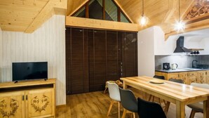 Un intérieur chaleureux et rustique, avec un espace repas, un téléviseur et une cuisine.