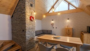 Un coin repas chaleureux avec un mur en pierre, un plafond en bois et une fenêtre de style industriel.