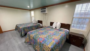 A hotel room with two beds, a window, an air conditioning unit, and a wooden cabinet. - Hilltop Motor Inn (Los Angeles)