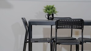 Un comedor con una mesa y cuatro sillas, una planta en maceta sobre la mesa y un interruptor de luz en la pared.