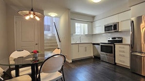 A modern kitchen with stainless steel appliances, a glass dining table, and white cabinetry. - A Modern and Executive Unit~1 Parking Spot&Great Location - Close To Everything (London)