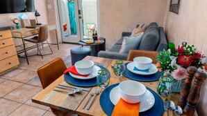 A dining area with a table set for four, including plates, bowls, cutlery, and glasses. - Studio Near Santa Fe Farmers Market (Santa Fe)